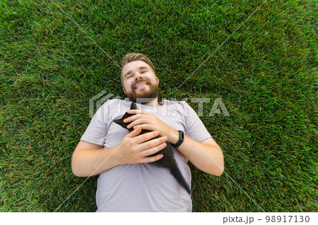 Man with little kitten lying and playing on grass - friendship love animals and pet owner concept 98917130