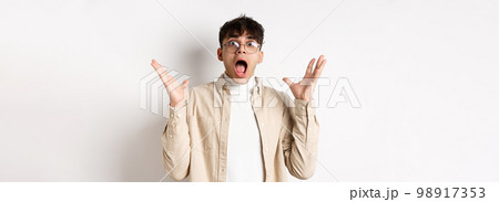 Scared young man in panic, screaming and looking axious, jumping startled and shocked, shaking hands nervously, standing on white background Scared young man in panic, screaming and looking axious, jumping startled and shocked, shaking hands nervously, standing on white background 98917353