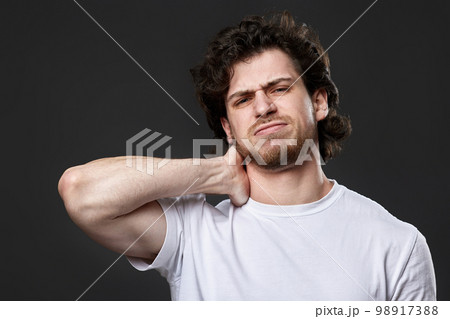 young man with neck pain on dark gray background 98917388