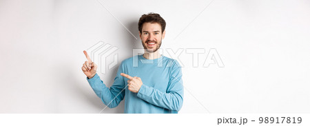Happy bearded man showing advertisement, pointing fingers right and smiling, inviting to click link, standing over white background Happy bearded man showing advertisement, pointing fingers right and smiling, inviting to click link, standing over white background 98917819