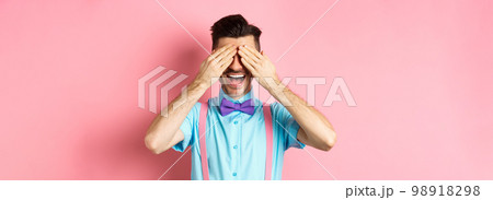 Cheerful young man celebrating, waiting for surprise with closed eyes and happy smile, standing joyful on pink background Cheerful young man celebrating, waiting for surprise with closed eyes and happy smile, standing joyful on pink background 98918298