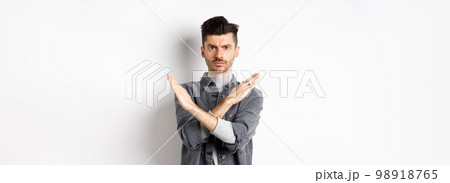 Angry man show cross gesture to stop or say no, frowning and looking serious, disagree and prohibit bad situation, standing on white background 98918765