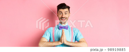 Image of smiling young man asking please, looking grateful at camera, Guy in bow-tie say thank you, standing over pink background 98919885