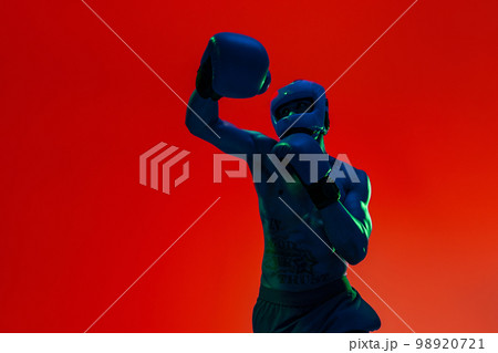 Sporty man wearing head guard and boxing gloves practicing for fight on studio background 98920721