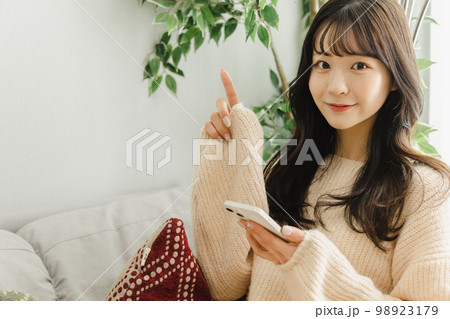 スマートフォン　指差しをする女性　 98923179