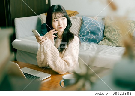 スマートフォンとノートパソコンを使う若い女性 98923382