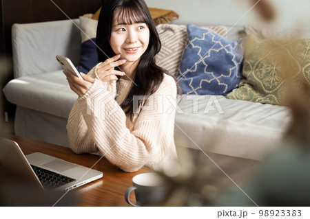 スマートフォンとノートパソコンを使う若い女性 98923383
