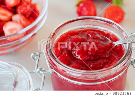 Preparation and preservation of strawberry jam in a glass jar, close up 98923563