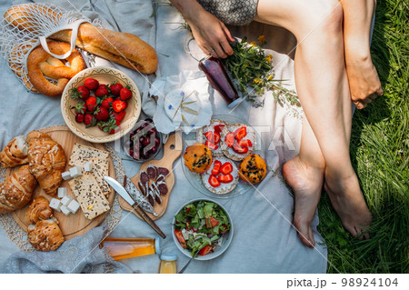 Beautiful woman on picnic. She smiles, eats strawberries and enjoys summer. Beautiful woman on picnic. She smiles, eats strawberries and enjoys summer. 98924104