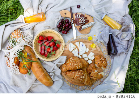 Picnic in the field with berries, juice, cheese, sausage and sweet croissants Picnic in the field with berries, juice, cheese, sausage and sweet croissants 98924116
