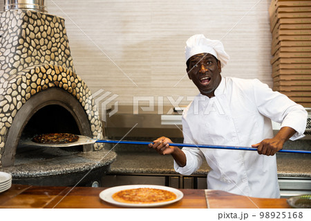 Emotional man chef preparing pizza in pizzeria Emotional man chef preparing pizza in pizzeria 98925168