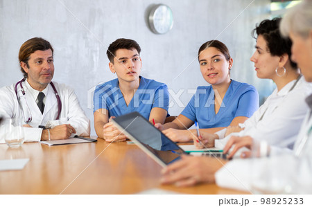 Doctors discussing diagnosis during medical council at table Doctors discussing diagnosis during medical council at table 98925233
