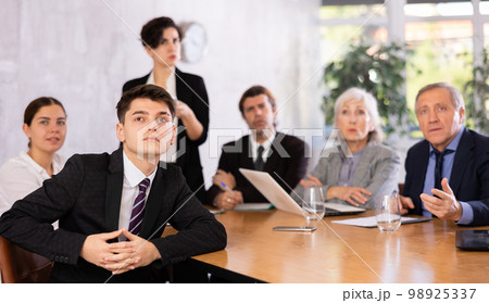 Woman and man sitting at table beside during meeting in conference room Woman and man sitting at table beside during meeting in conference room 98925337