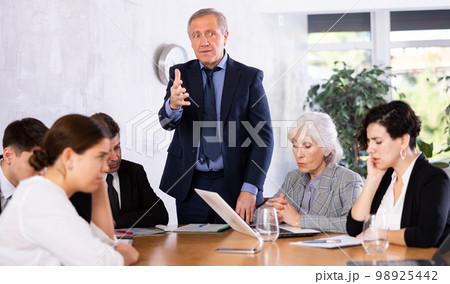 Portrait of angry male boss in business suit pointing to the door to his subordinate during meeting forcing him 98925442
