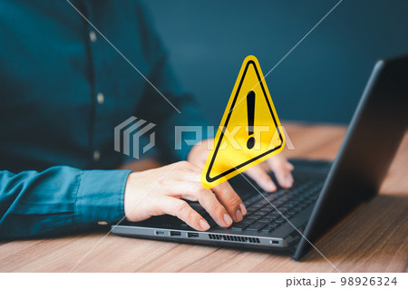Adult man using computer laptop with triangle caution warning sign for notification error. Computer virus detected, personal data protection, network security and maintenance concept. Adult man using computer laptop with triangle caution warning sign for notification error. Computer virus detected, personal data protection, network security and maintenance concept. 98926324