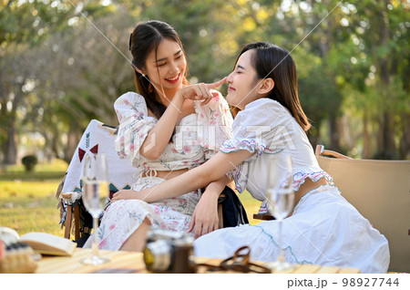 Two beautiful Asian female besties cuddle, playing, sharing a special moment together Two beautiful Asian female besties cuddle, playing, sharing a special moment together 98927744