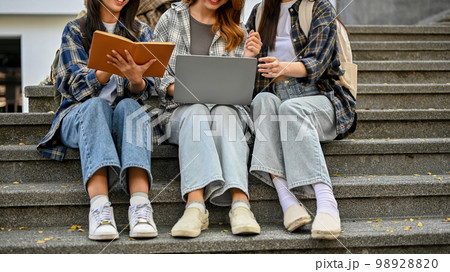 Cropped image of group of young Asian female college students sitting on street stairs Cropped image of group of young Asian female college students sitting on street stairs 98928820