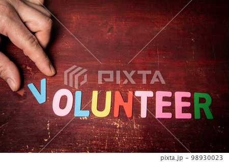 VOLUNTEER. Text from colorful letters on a wooden background 98930023