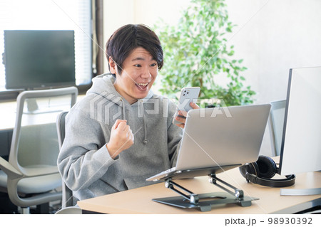 ガッツポーズをする若い男性 98930392