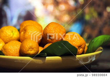 Ripe tangerines in a yellow plate on a wooden table Ripe tangerines in a yellow plate on a wooden table 98930664