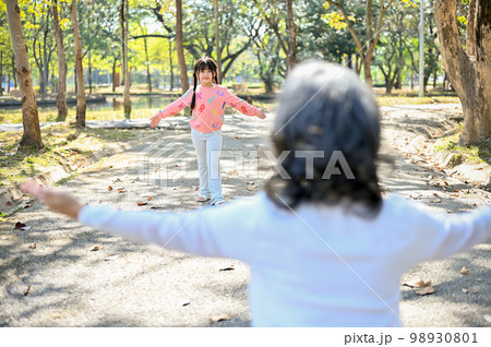 An adorable Asian granddaughter running to her grandmother, playing fun game in the park 98930801