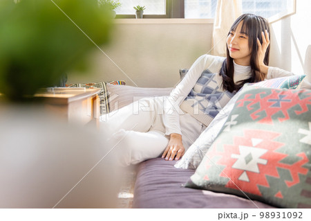ローソファーでくつろぐ若い女性 98931092