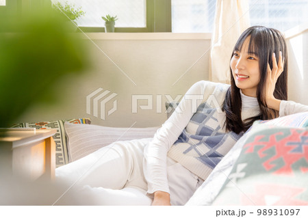 ローソファーでくつろぐ若い女性 98931097