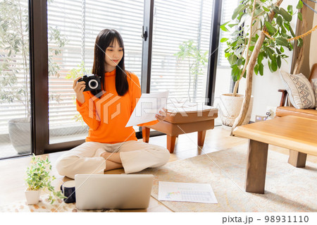 床に座り仕事をする若い女性 98931110