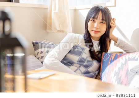 ローソファーでくつろぐ若い女性 98931111