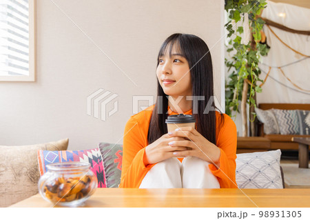 膝を立てコーヒー・紅茶を飲む若い女性 98931305
