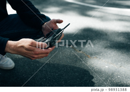 Man holds remote controller with his hands and controls the drone. Man holds remote controller with his hands and controls the drone. 98931388