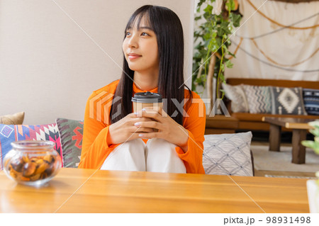 膝を立てコーヒー・紅茶を飲む若い女性 98931498