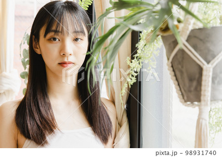 窓辺に立つ若い女性 98931740