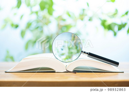 テーブルの上に開いた本とルーペ テーブルの上に開いた本とルーペ 98932863
