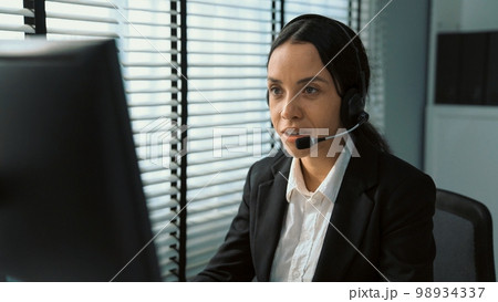 Competent female operator working on computer and while talking with clients. Competent female operator working on computer and while talking with clients. 98934337