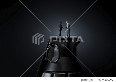 おもちゃの手榴弾と握手をするミニチュア人形 98936325