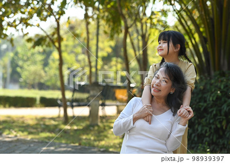 Loving middle aged woman and little granddaughter enjoying leisure weekend time at outdoor surrounded by beautiful nature view Loving middle aged woman and little granddaughter enjoying leisure weekend time at outdoor surrounded by beautiful nature view 98939397