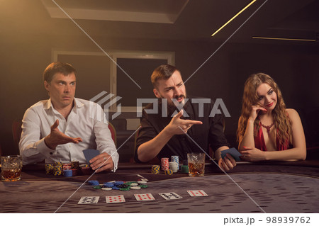 Group of a young wealthy friends are playing poker at a casino. Group of a young wealthy friends are playing poker at a casino. 98939762
