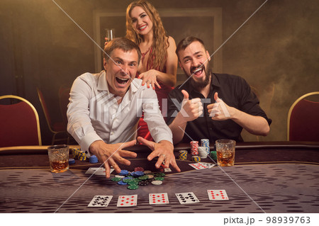 Group of a young wealthy friends are playing poker at a casino. Group of a young wealthy friends are playing poker at a casino. 98939763