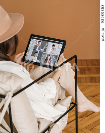 Home e-learning. Video lesson. Online education. Internet conference. Relaxed woman watching diverse students group on tablet screen. Home e-learning. Video lesson. Online education. Internet conference. Relaxed woman watching diverse students group on tablet screen. 98939868