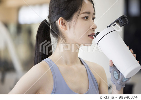 スポーツジムでトレーニング後プロテインを飲む若い女性 スポーツジムでトレーニング後プロテインを飲む若い女性 98940374