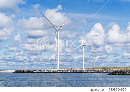 Wind turbines on the shore against cloudy sky 98940492