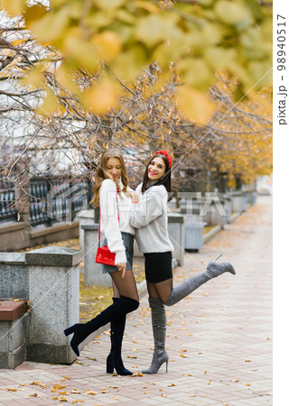 Photos of two girls, charming friends walking in the autumn park, enjoying the weather Photos of two girls, charming friends walking in the autumn park, enjoying the weather 98940517