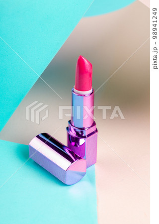 Vertical shot close up of pink lipstick. Reflective purple cap. Vertical shot close up of pink lipstick. Reflective purple cap. 98941249