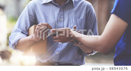 Close up of Asian Man signing his name by hand to accept a delivery package and a smartphone. logistical delivery concept Close up of Asian Man signing his name by hand to accept a delivery package and a smartphone. logistical delivery concept 98943076