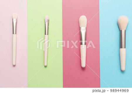 Set of makeup brushes on pink, blue, green, coral colored background. Top view, flat lay. Set of makeup brushes on pink, blue, green, coral colored background. Top view, flat lay. 98944969