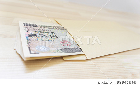 テーブルの上に置かれた封筒に入った一万円札 テーブルの上に置かれた封筒に入った一万円札 98945969