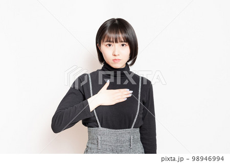 胸に手を当てている若い女性 胸に手を当てている若い女性 98946994