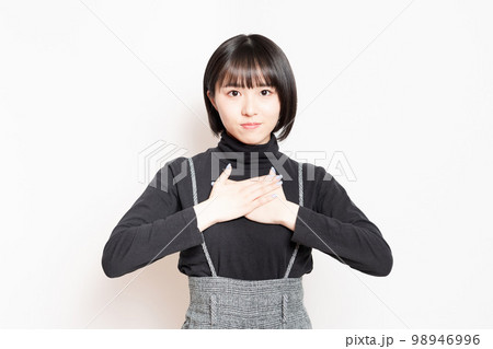 胸に手を当てている若い女性 98946996