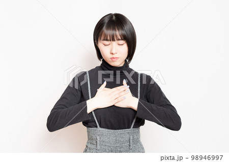 胸に手を当てている若い女性 98946997